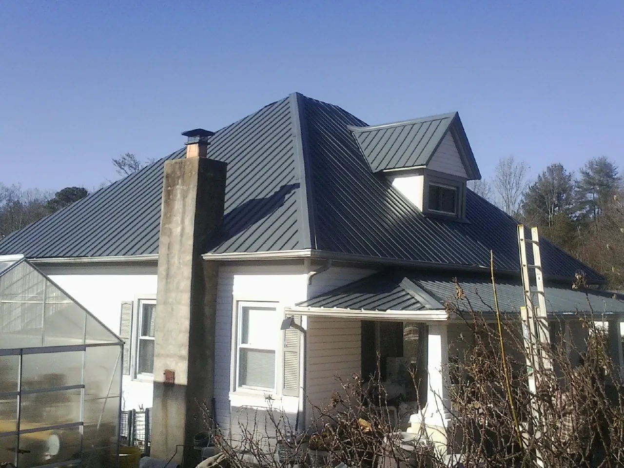 Dark blue standing seam metal roof on a white farmhouse with dormer — Slate & Tile Roof Repair by Roofing Brothers in Riggins