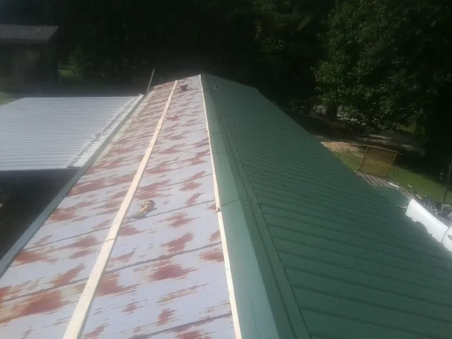 Old rusted panels beside newly installed green metal roofing — Wind Damage Roof Repair by Roofing Brothers in Riggins