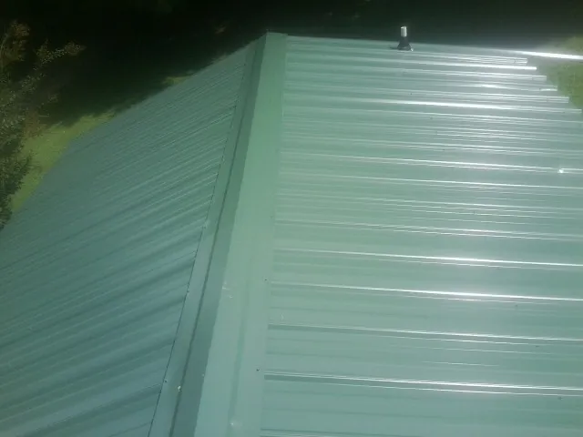 New green metal panels meeting at the ridge of a roof — Flat Roof Repair work by our crew in Riggins