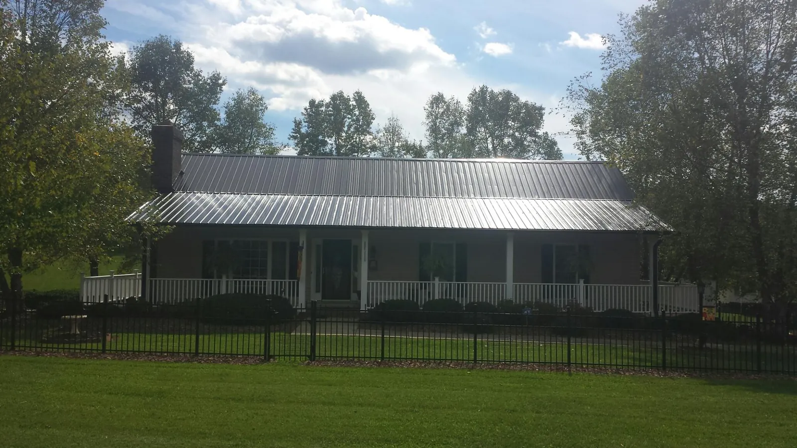Gray metal roof on a brick ranch with a full width front porch — Gutter Guard Installation work by our crew in Riggins
