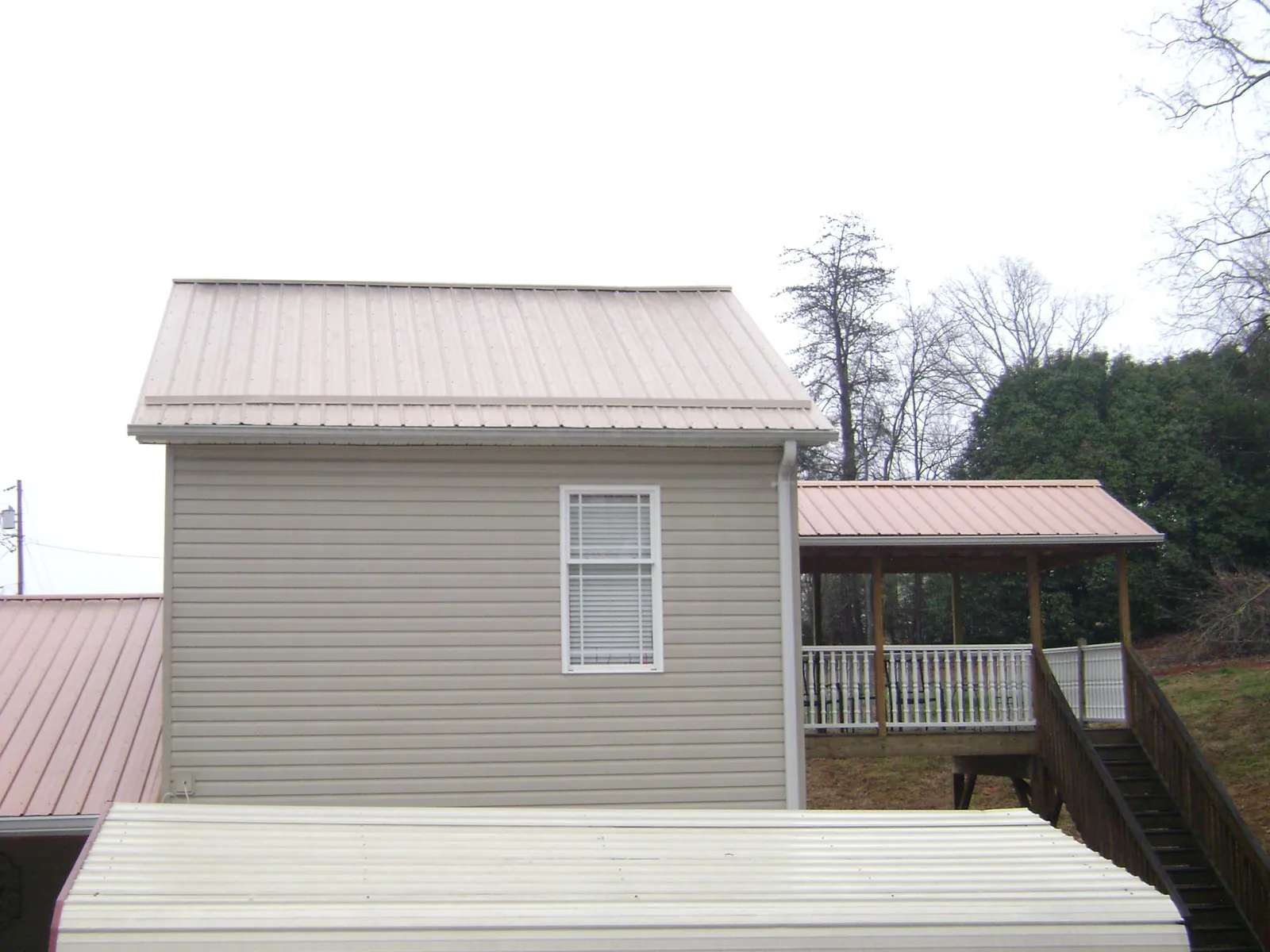 Tan metal roofs on a two story addition and attached porch, from a Roof Replacement job in Riggins